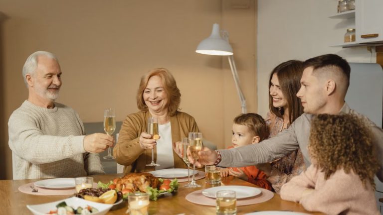 A joyful family toasts together over a festive dinner with champagne indoors.